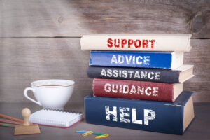 Support concept. Stack of books on wooden desk. the books are labeled "support, advice, assistance, guidance, and help"