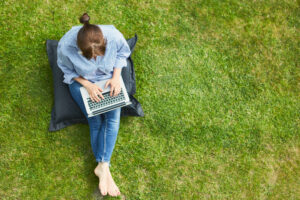 Woman working on laptop in summer in the grass